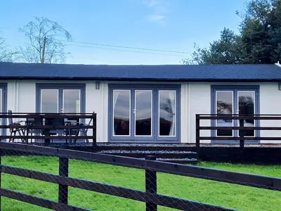 a white house with a fence in front of it at Beautiful Countryside Lodge with Outstanding Views - Pass the Keys in Dumfries