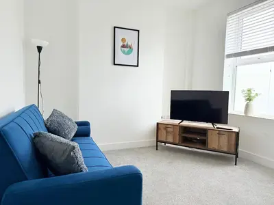 a living room with a blue couch and a flat screen tv at Workington Home - Working - Visiting the Lakes in Workington