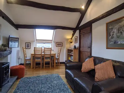 a living room with a leather couch and a table at Oakside Cottage Braithwaite in Braithwaite