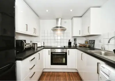 a kitchen with white cabinets and black counter tops at The Igloo Viewoint City Centre Stay & Free Parking in Moffat