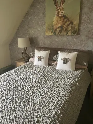 a bed with two pillows and a picture of a rabbit at The Bee Hive Hotel in Coylton