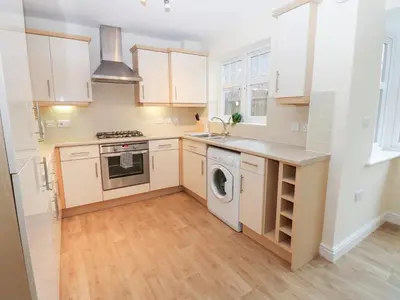 a kitchen with white cabinets and a washer and dryer at Linga House - 3 Bedrooms - Sleeps 5 in Frizington
