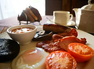 a plate of breakfast food with eggs bacon and tomatoes at Manor House Hotel, Cockermouth in Cockermouth