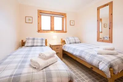 a bedroom with two beds and a mirror at Shellhill Cottage at Clauchan Holiday Cottages in Gatehouse of Fleet