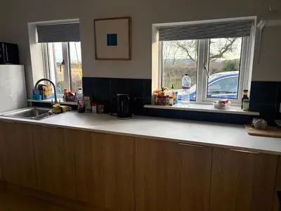 a kitchen counter with a sink and two windows at Mains of Greenlaw Cottage in Castle Douglas
