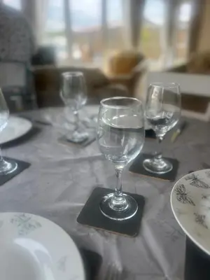 a table with four wine glasses and plates on it at Skiddaw Lodges- The Lake District in Plumbland
