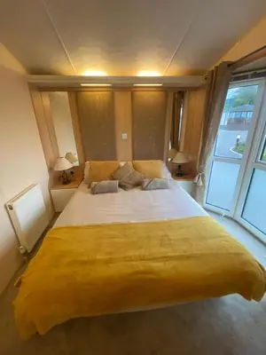 a large yellow bed in a room with a window at Skiddaw Lodges- The Lake District in Plumbland