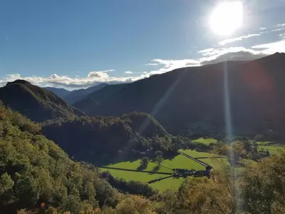 a valley in the mountains with the sun shining at Field House in Keswick