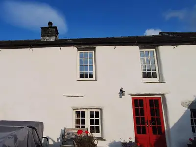 a white house with a red door and windows at Field House in Keswick