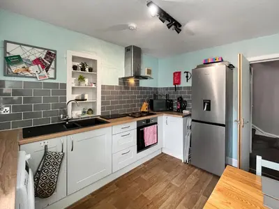 a kitchen with white cabinets and a stainless steel refrigerator at Fleet Townhouse in Gatehouse of Fleet