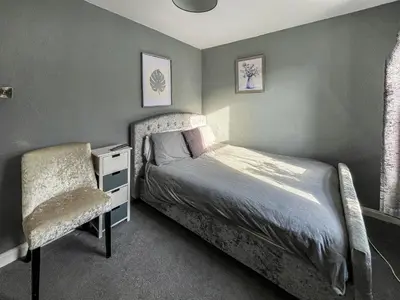 a small bedroom with a bed and a chair at Fleet Townhouse in Gatehouse of Fleet