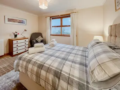 a bedroom with a bed and a dresser and a window at Shellhill Cottage in Kirkcudbright