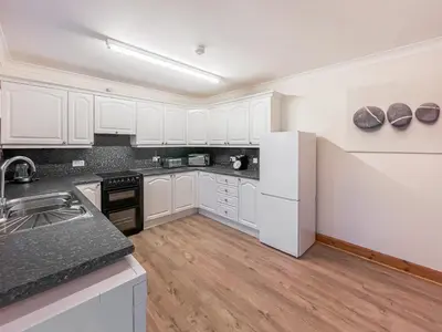 a kitchen with white cabinets and a white refrigerator at Shellhill Cottage in Kirkcudbright
