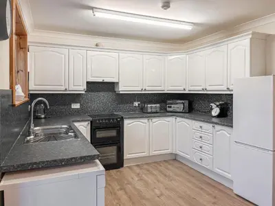 a kitchen with white cabinets and black counter tops at Shellhill Cottage in Kirkcudbright