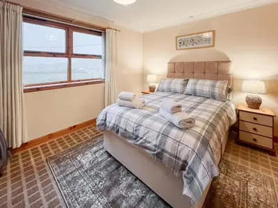 a bedroom with a bed and a window at Shellhill Cottage in Kirkcudbright