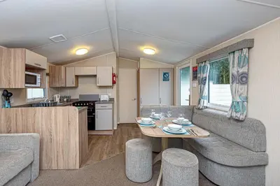 a living room and kitchen with a couch and a table at Lyons Manor House Caravan Park in Mawbray