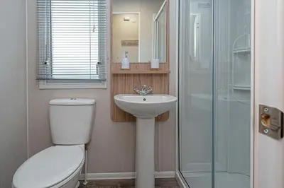 a bathroom with a toilet and a sink and a shower at Lyons Manor House Caravan Park in Mawbray