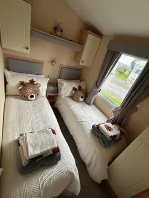 two beds in a small room with teddy bears on them at 28 The Beeches in Wigton