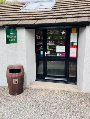 a shop with a trash can in front of it at 28 The Beeches in Wigton
