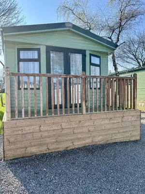 a small green house with a wooden fence at 28 The Beeches in Wigton