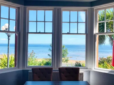 a dining room with windows looking out at the ocean at Burlington Guest House in Whiting Bay