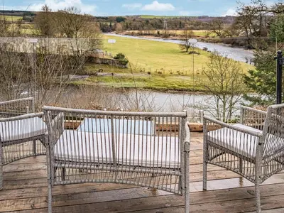 two benches sitting on a deck overlooking a river at Prior Bank in Canonbie