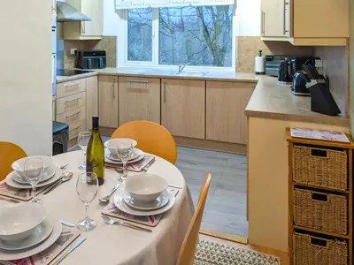 a kitchen with a table with plates and wine glasses at Prior Bank in Canonbie