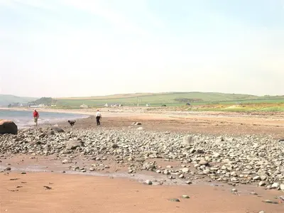 two people walking on a beach with rocks at Airyolland in Newton Stewart