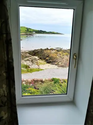 a window in a door looking out at the ocean at Albany Cottage in Rockcliffe