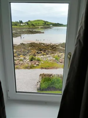 a window with a view of a beach at Albany Cottage in Rockcliffe