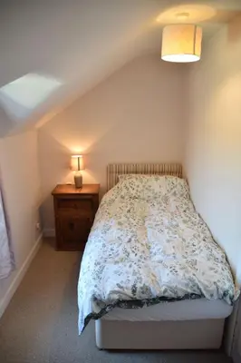 a small bedroom with a bed and a night stand at Albany Cottage in Rockcliffe