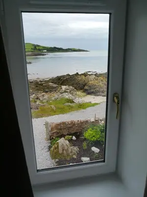 a window view of a beach from a door at Albany Cottage in Rockcliffe