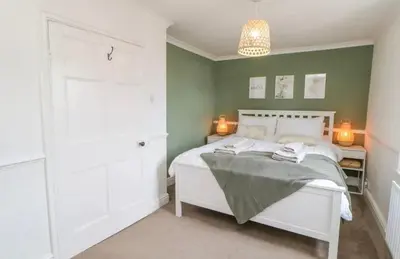 a bedroom with a white bed and a green wall at Ploughmans Cottage in Brampton