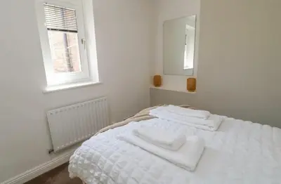 a white bedroom with two white towels on a bed at Ploughmans Cottage in Brampton