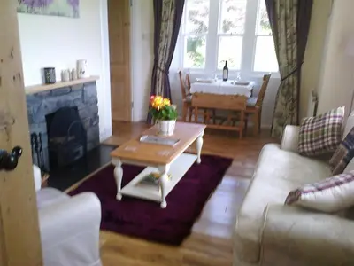 a living room with a couch and a table with a fireplace at Ardwell House East Lodge in Stranraer