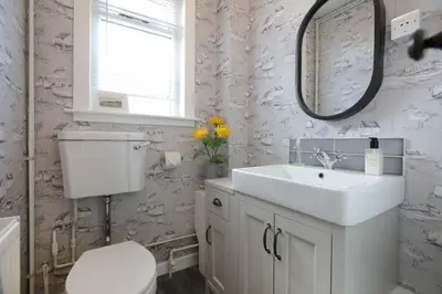 a bathroom with a sink and a toilet and a mirror at Allonby Cottage in Kippford