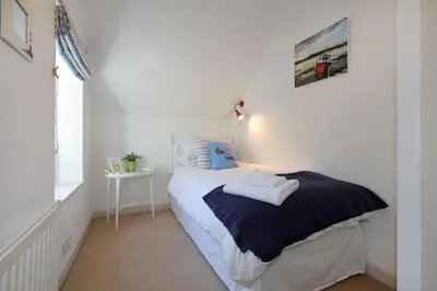 a white bedroom with a bed with towels on it at Allonby Cottage in Kippford