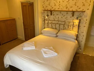a bedroom with a white bed with towels on it at Berkeley House in Keswick
