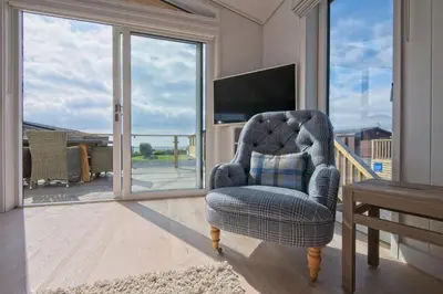 a blue chair in a living room with a sliding glass door at Bluebell Lodge in Girthon