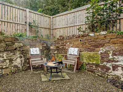 a garden with two benches and a stone wall at 1 Bed in Maybole 93562 in Maybole