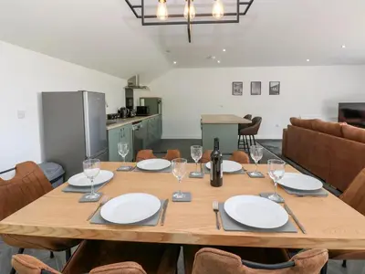 a wooden table with plates and wine glasses on it at Oaktree Cottage - 3 Bedrooms - Sleeps 6 in Frizington