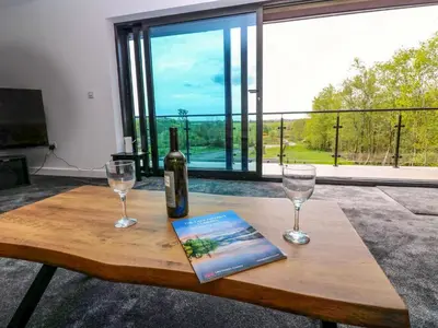 a bottle of wine and two glasses on a wooden table at Oaktree Cottage - 3 Bedrooms - Sleeps 6 in Frizington