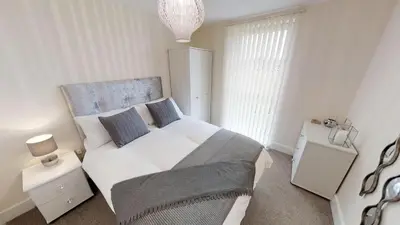 a bedroom with a large white bed and two night stands at Lovely Furnished Apartment 2 in Carlisle