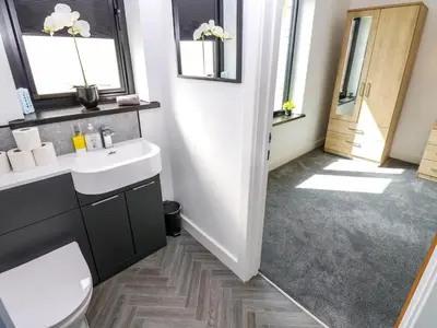 a bathroom with a sink and a toilet and windows at Sycamore Cottage - 2 Bedrooms - Sleeps 4 in Frizington