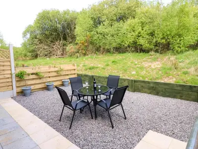 a patio with a table and chairs on gravel at Sycamore Cottage - 2 Bedrooms - Sleeps 4 in Frizington
