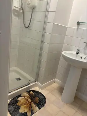 a bathroom with a sink and a shower with a flower rug at Athol House in Douglas