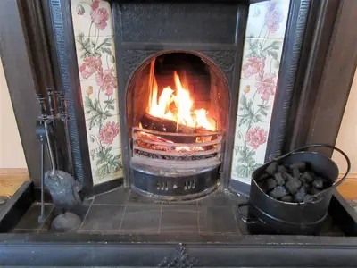 a fireplace with a fire inside of it at Allanhead Cottage in Kirkcudbright