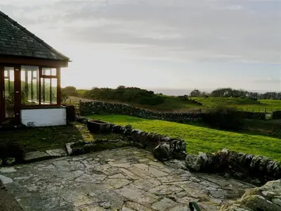 a stone path in front of a house with a stone wall at Allanhead Cottage in Kirkcudbright