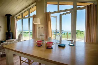 a wooden table in a room with a large window at Barley Lodge in Girthon