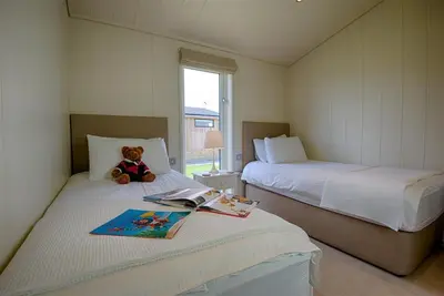 a teddy bear sitting on a bed in a bedroom at Barley Lodge in Girthon